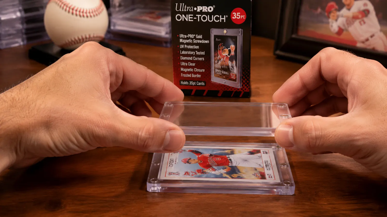 Hand snapping shut an Ultra Pro One Touch magnetic holder over a baseball card, demonstrating the tool-free magnetic closure